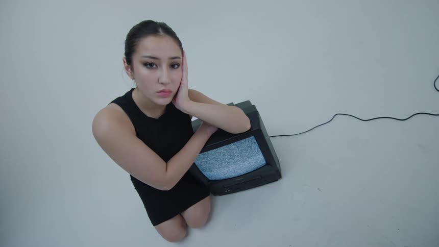 Portrait of a young woman modeling next to an old television