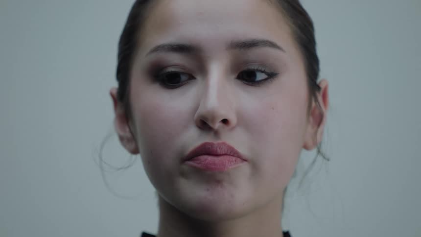 A face of a young woman that is looking to the sides without moving her head