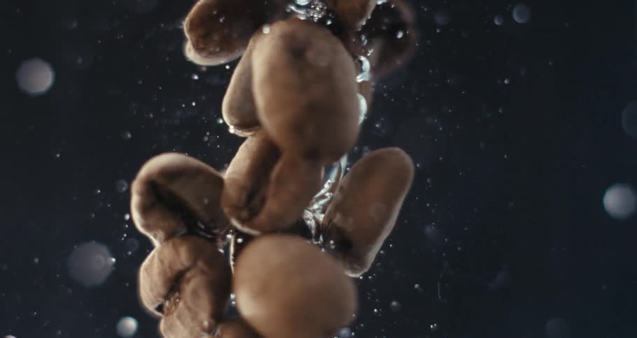 Extreme closeup of a spiral underwater with coffee beans in slow motion