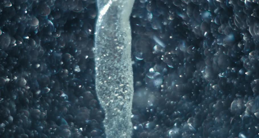 Extreme closeup of a shimmering underwater spiral causing impact and abstract bubbles