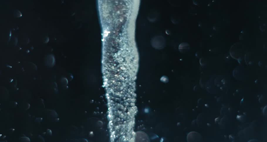Extreme closeup of a spiral underwater with bubbles and glows in slow motion