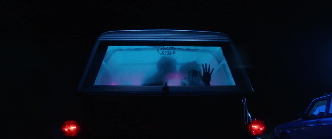 Silhouette of two people kissing in a car in the parking lot