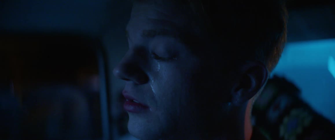 A young man is crying and tears fall from his eyes one night and something lights up his face