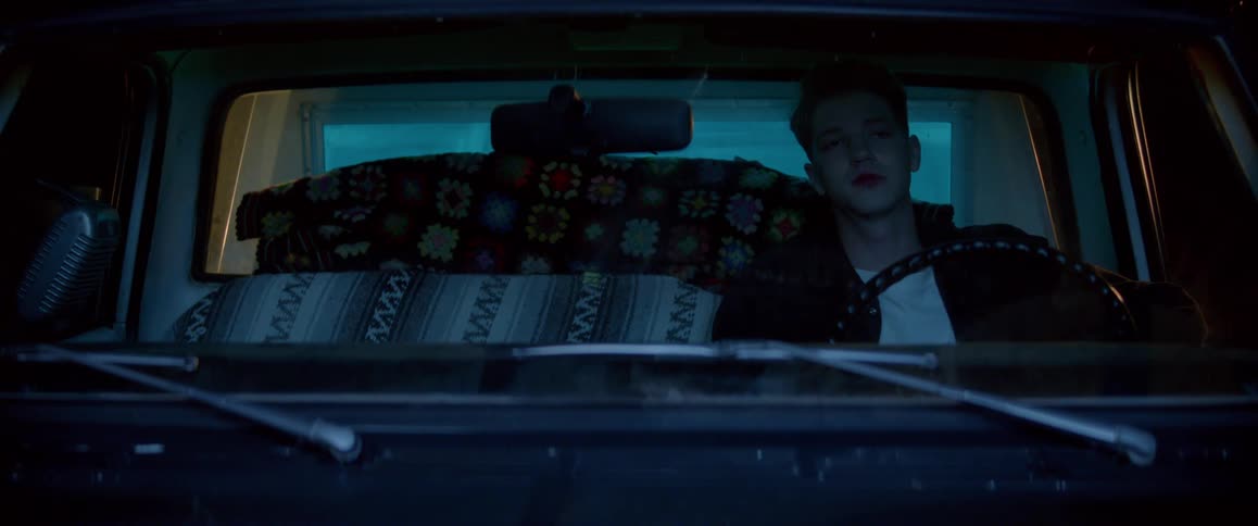 A young man sitting behind a stirring wheel of a truck