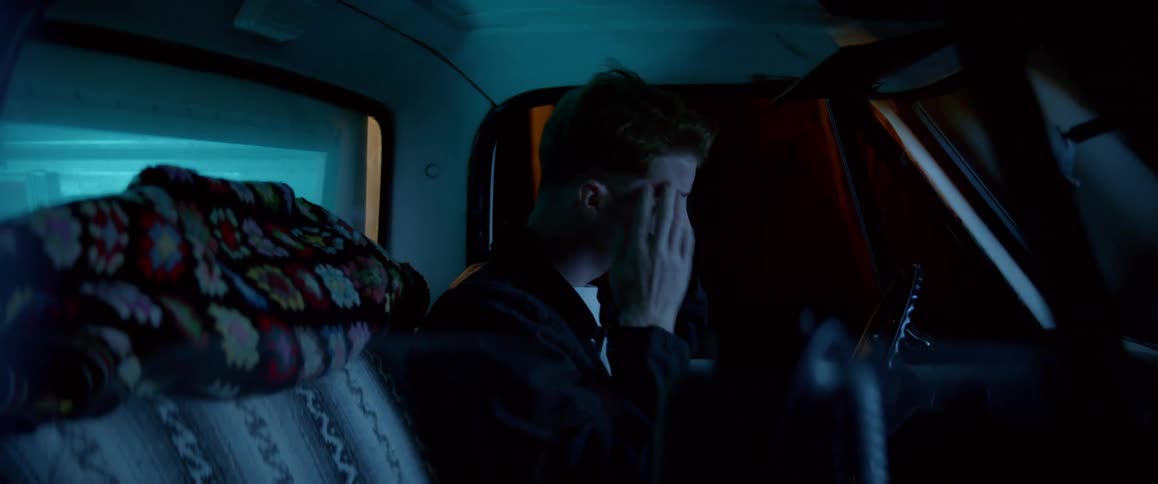 A heartbroken young man crying in the car at night