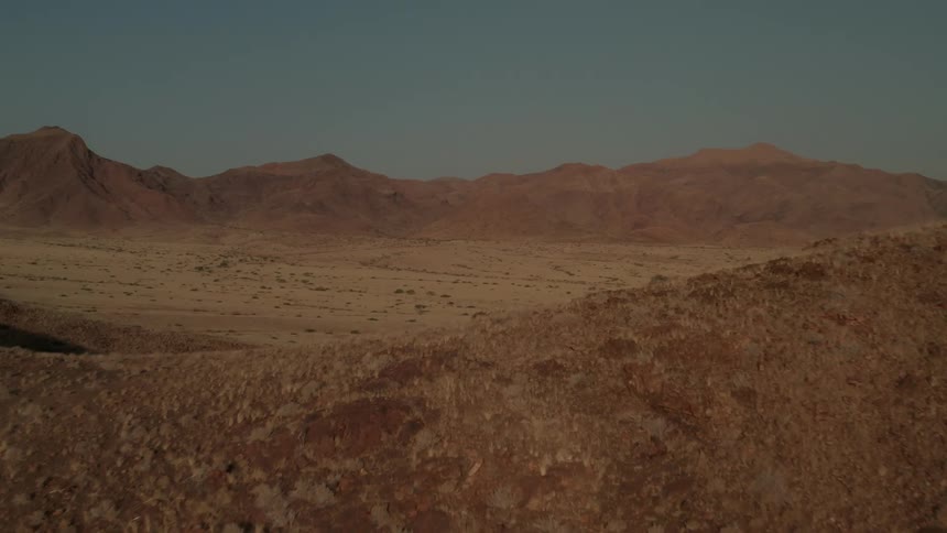 Aerial view of barren field surrounded by mountains in the desert