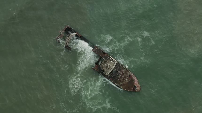 An aerial view of a grounded shipwreck weathered and stranded