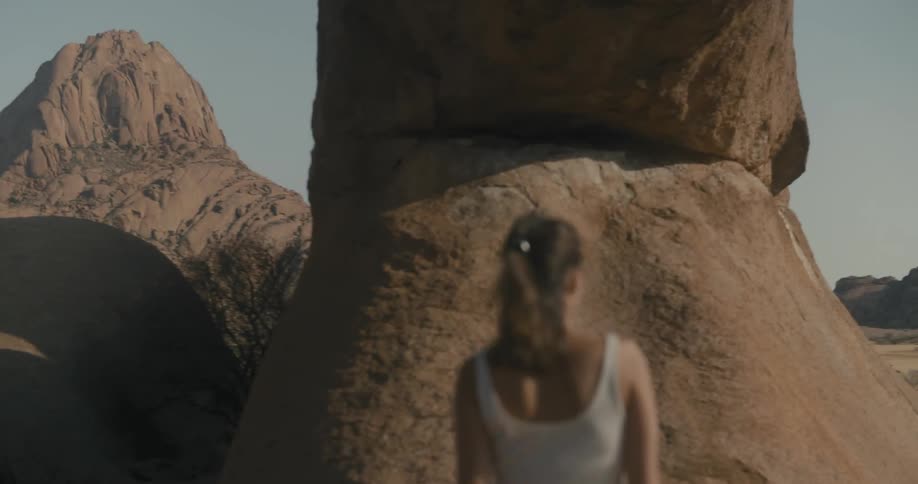 A woman walking in a desert landscape with mountains
