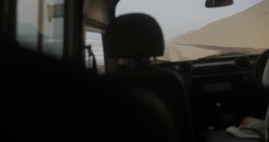 Car driving on the beach next to the ocean
