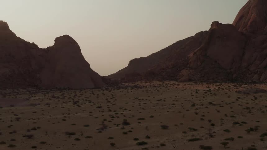 Aerial of a desert plain with red mountains