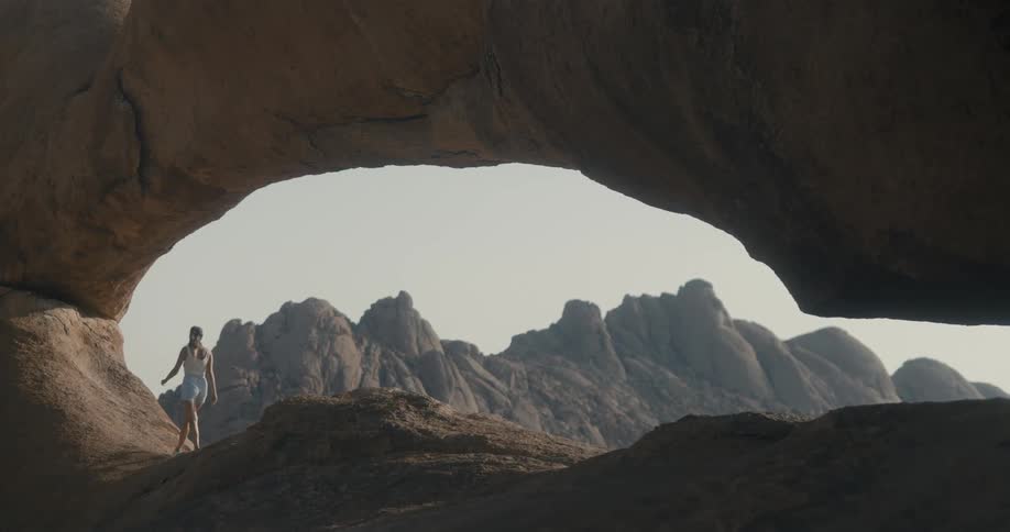 Woman walking away back facing under the rocks in a natural environment