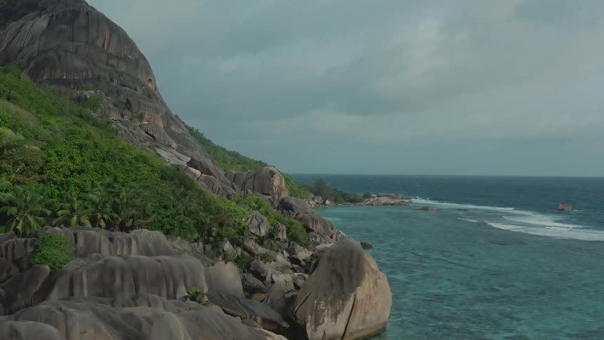 Waves roll into shore and splash against rocks along the coast at the foot of a promontory