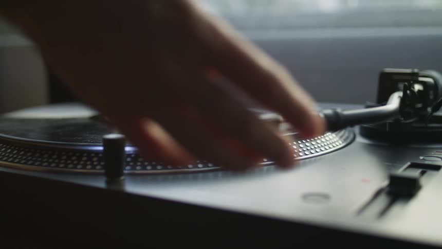 A person places a vinyl record on a vintage player