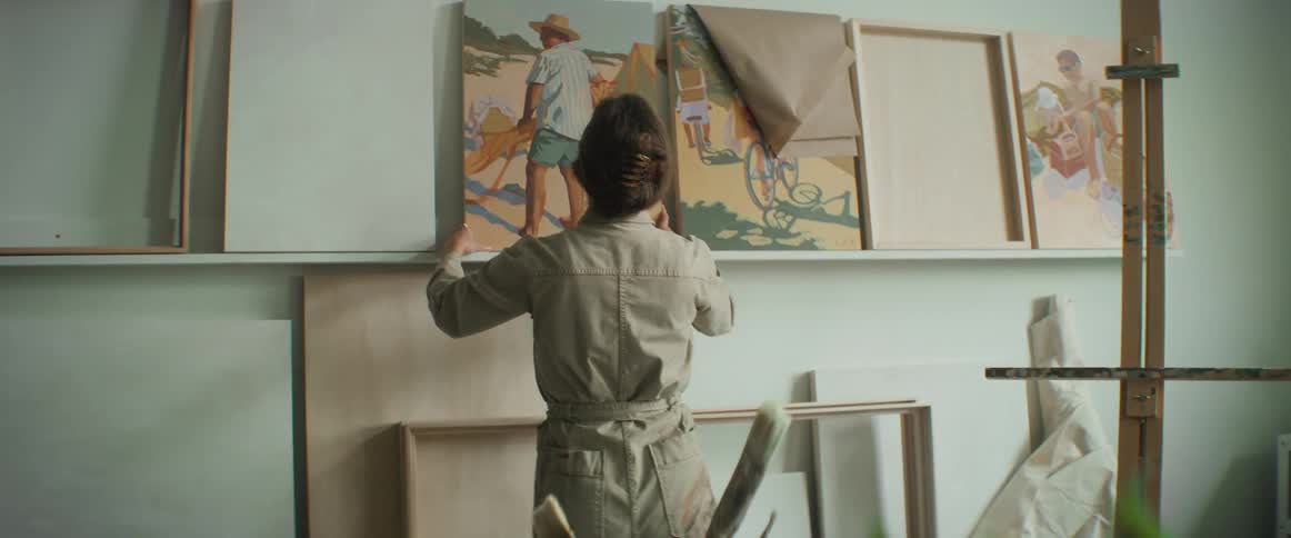 A woman places an artistic painting on a wall
