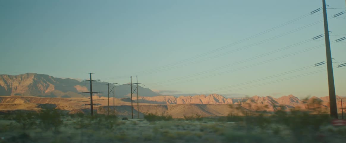 A vehicle driving left captures a mountain range under blue skies