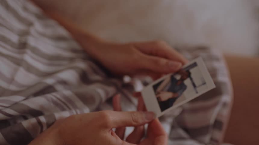 Closeup of a womans hands opening a book and a photo of a man falling out