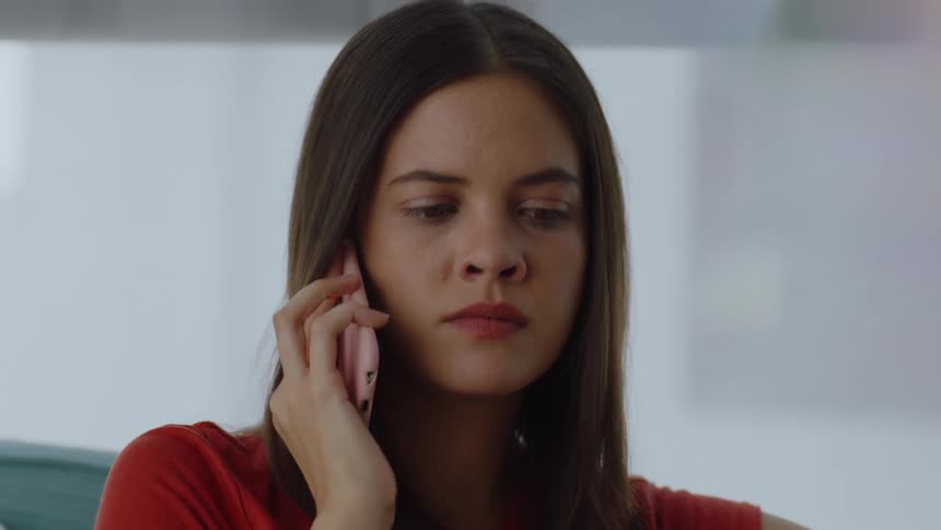 A woman with straight hair and a red shirt makes a phone call but there is no answer on the other end