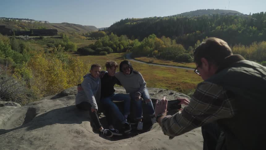 Family pose for a picture over a rock in a park