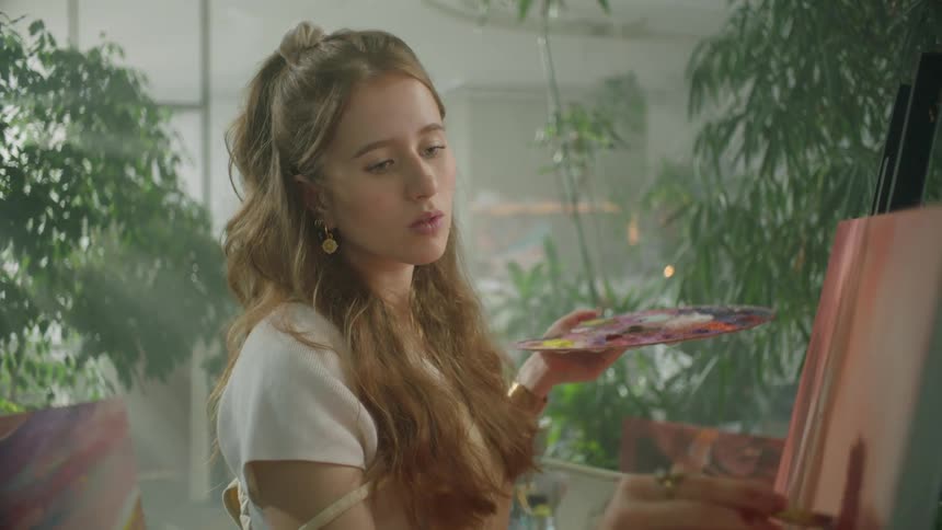 A woman painting indoor on a canvas