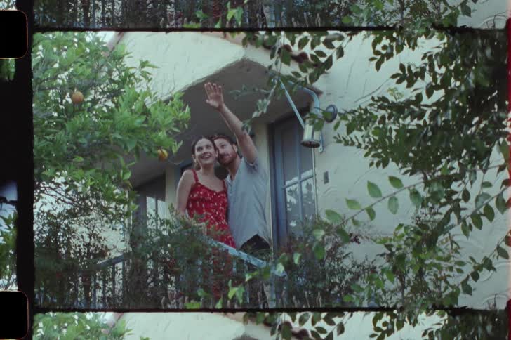 Man and woman standing on the balcony talking and cuddling at daytime