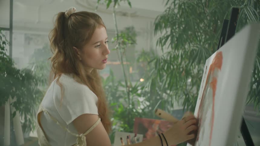 Artist uses a large brush to paint over canvas
