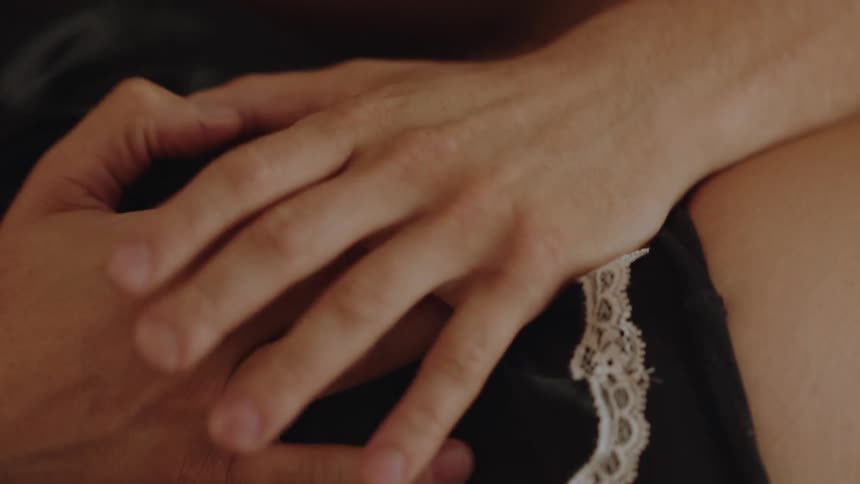 Couple lying in bed and holding hands