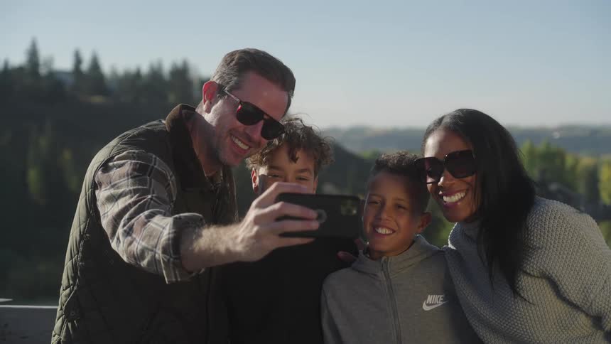 Family taking a selfie with a view of a natural environment with mountains and conifers