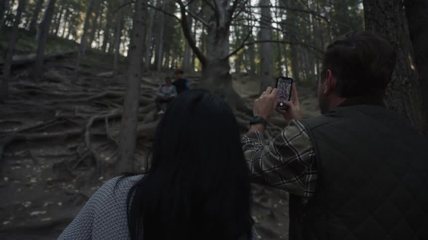 Family in the midst of a forest with the father taking a photo of his two children