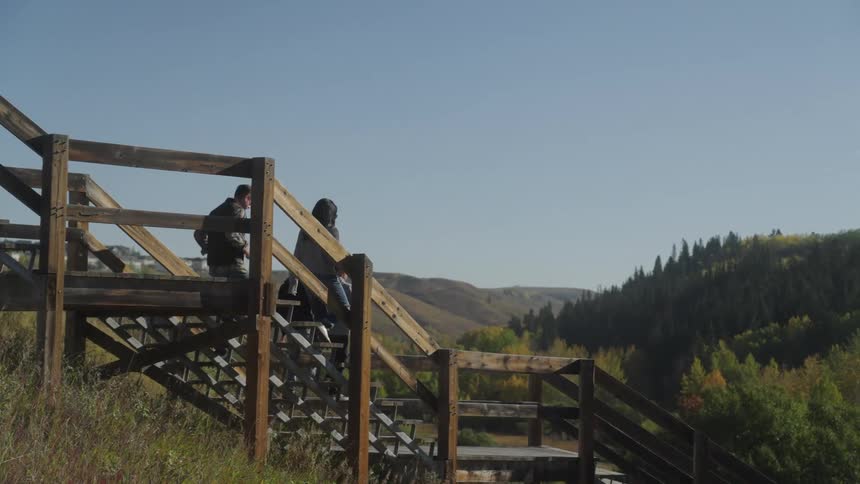 Family with two children descending a wooden staircase in a natural environment