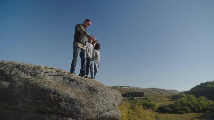 A small family admiring nature on top of a rock