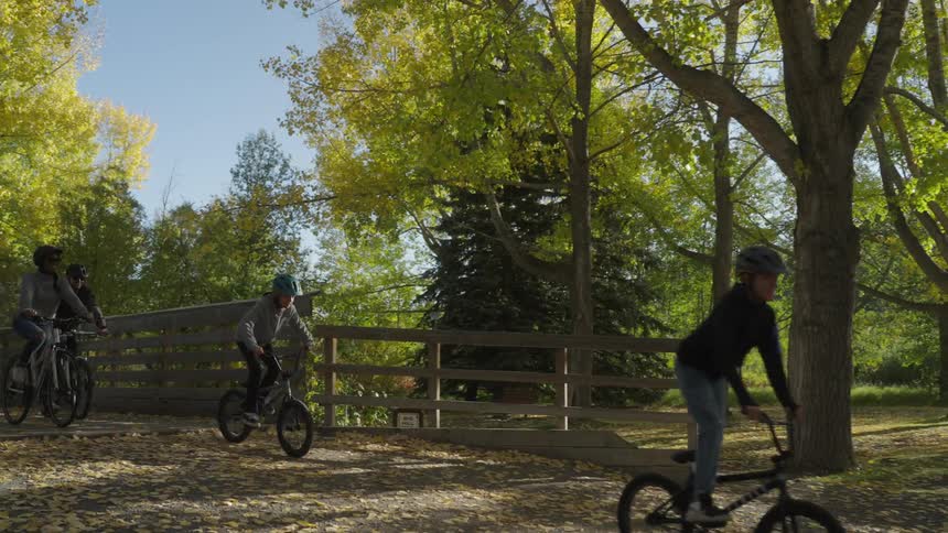 Family riding bicycles over a bridge on a park
