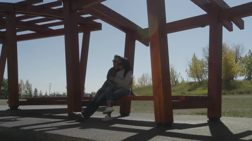 Couple sitting on a bench under a pergola at a park