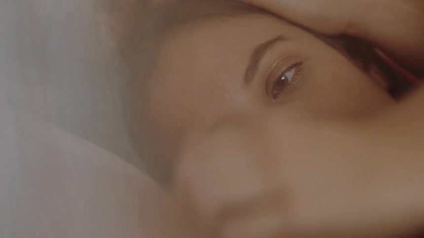 Woman strokes mans arm as they lie cuddling together