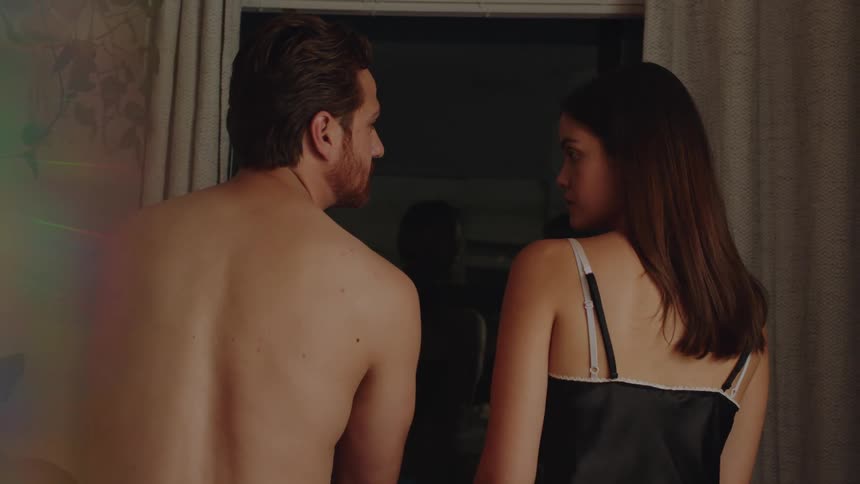 Woman strokes mans face and he looks away at night at home