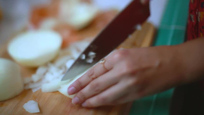 A woman is cutting some onions