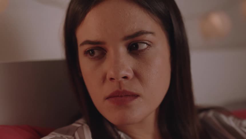 A sad and angry woman lying in bed