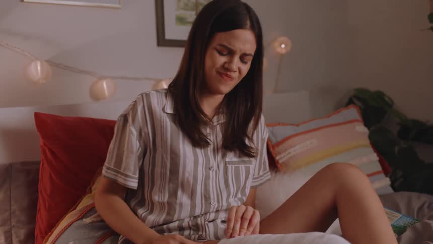 A woman with a casting sitting on the bed sad