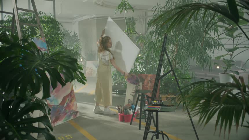 Artist takes a canvas and places it on an easel