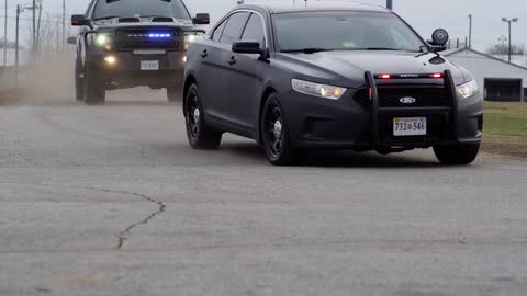View of a fleet of special police cars passing through a street on a cloudy day