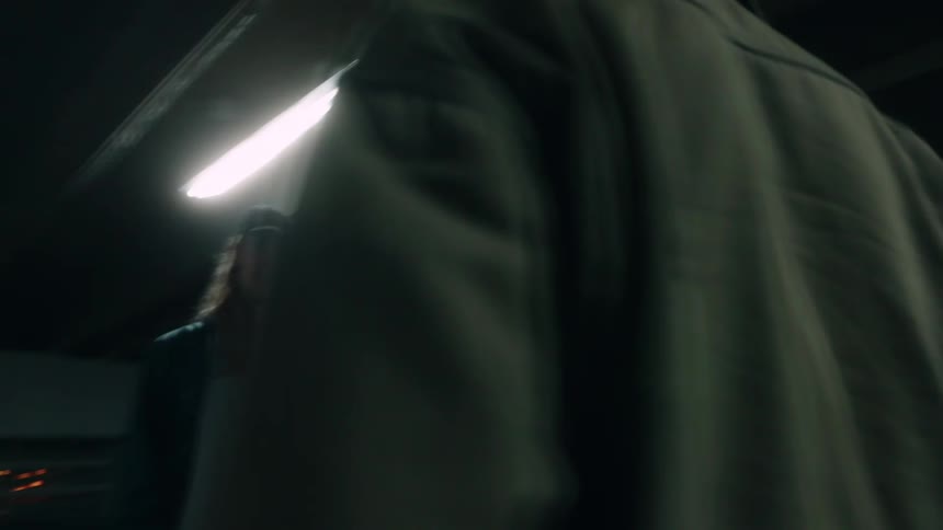 Two men stand facing off in parking garage at night