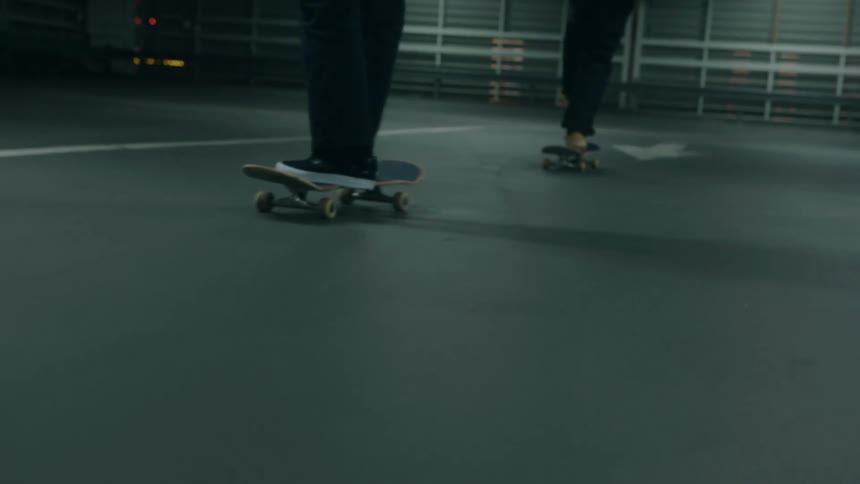Two teenagers are riding their skateboards in a parking garage at night