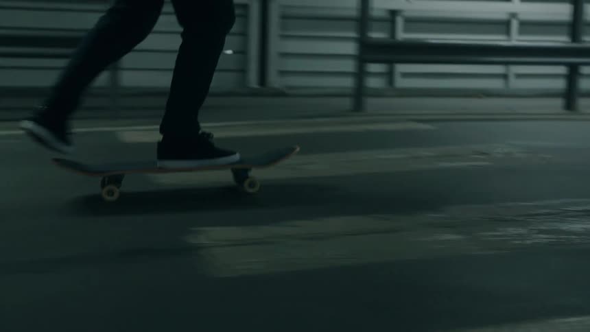 Two friends skateboarding in a parking garage near a sign indicating exit and elevator in swedish