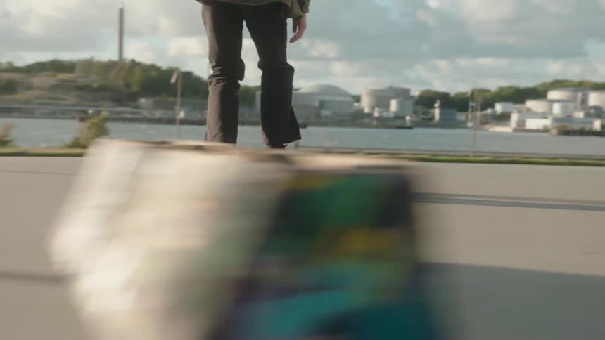 A teenager is running with his skateboard and lays it near the ground and jumps on but loses footing during a failed stunt attempt