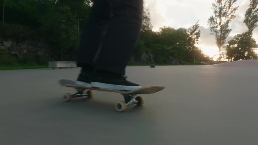 Man with green jacket black pants and shoes skateboards in skatepark doing hardflip