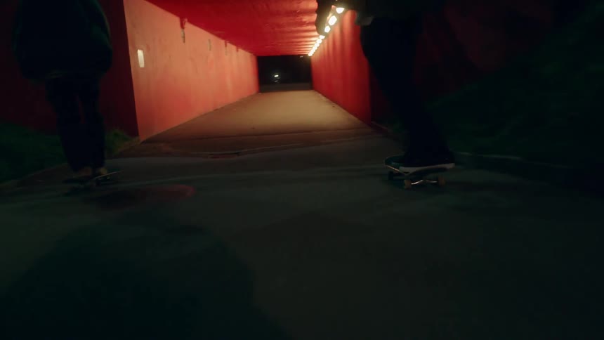 Two people are skateboarding outdoors at night