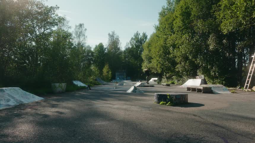 Male skateboarder with long hair cap black top and green pants skateboards in skateboarding park