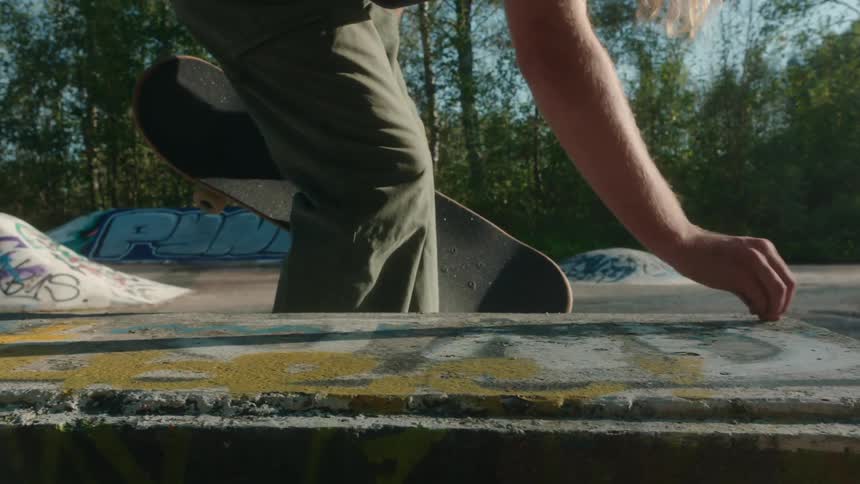 Skateboarder draws on concrete in skatepark using chalk while holding a skateboard