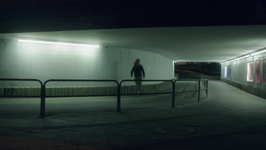 A man rides a skateboard through a pedestrian tunnel