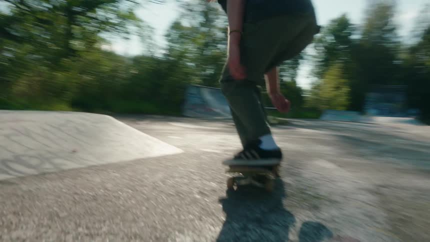 Young man riding a skateboard jumps a cement ramp on a skate park at morning