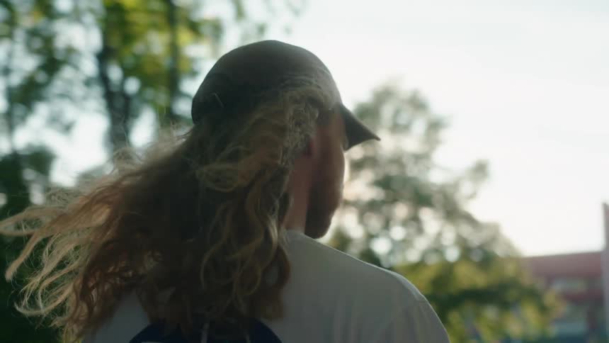 A young white man is on his skateboard outdoors in the daytime